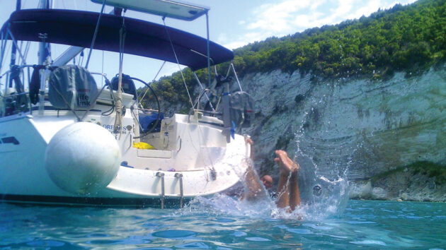 Man diving into the water from a yacht at Loutrolimni Beach or Barbarezou according to the Navily app