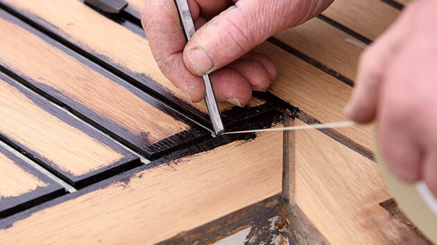a narrow chisel being used on a teak deck
