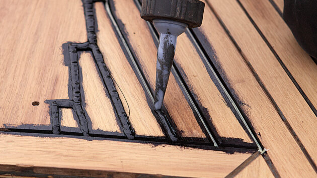 Caulking being injected into the seam of a teak deck