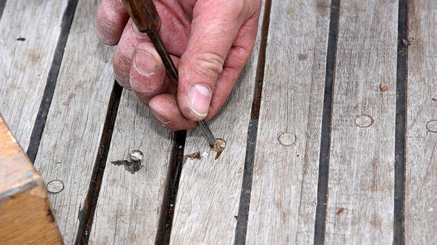 A man removing a plug from a boat deck