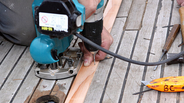 A man using a router roe remove a teak plank