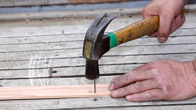 A hammer being used to hammer in a nail