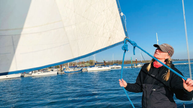 A woman sorting out lines on a sailboat sail