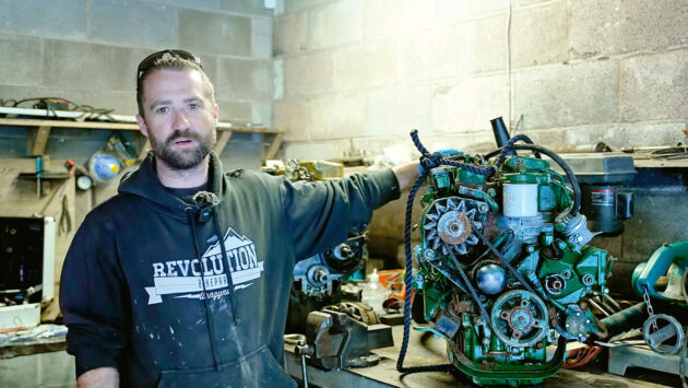 A man standing next to a boat engine