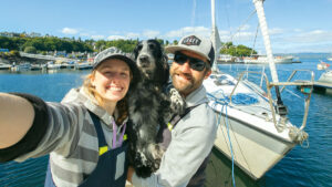 A couple and their dog smiling next to their Etap 30 yacht