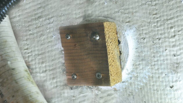 A wooden block screwed onto the hull of a boat after a failed seacock