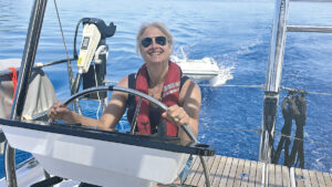 Smiling woman wearing a lifejacket at the helm of a yacht. Credit: Katy Stickland/Future Plc
