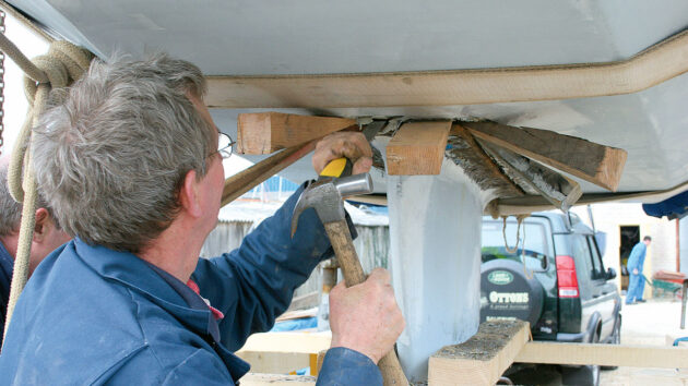 A man trying to remove a keel from a yacht