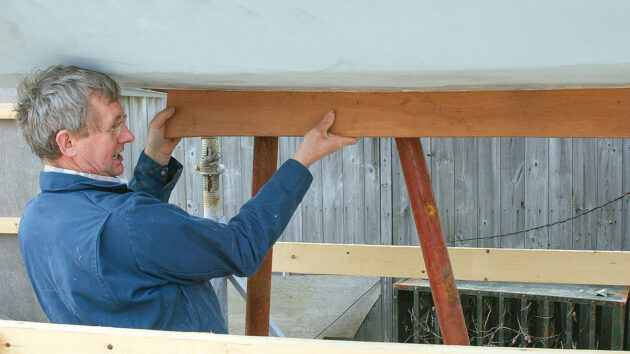 A man making a wooden template for a boat keel