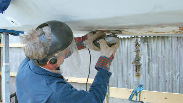 a man using an angle grinder to smooth the underside of a keel