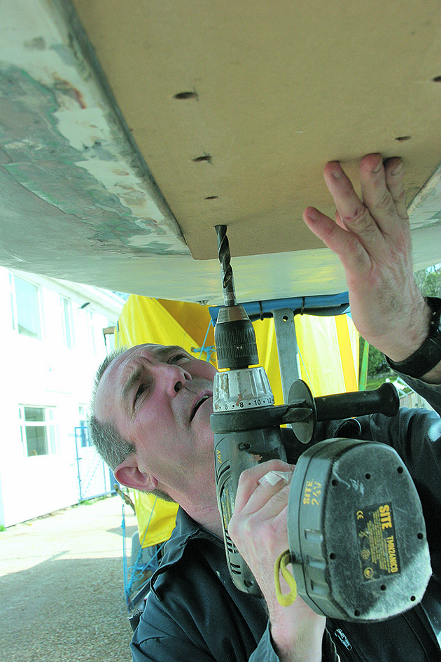 A man drilling into the hull of a boat
