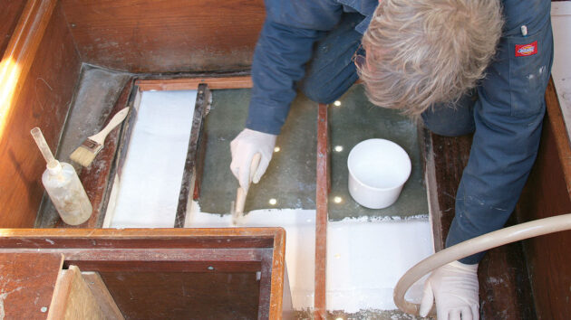 a man painting gel coat in the inside of a boat