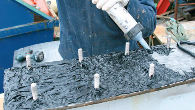 A man applying Sixaflex to a keel stub and keel bolts