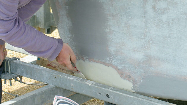 a man filling and fairing chips on a yacht keel