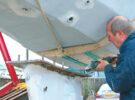A man doing maintenance on the keel and keel bolts on a yacht