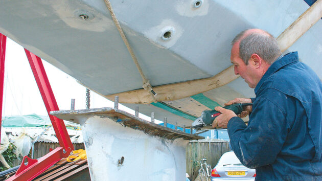 A man doing maintenance on the keel and keel bolts on a yacht