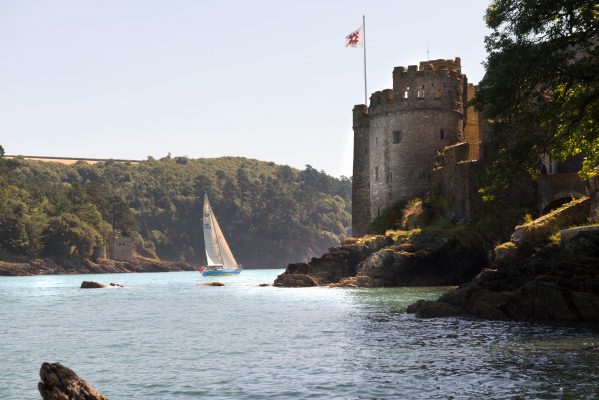 A yacht in full sail passing the castle on the River Dart