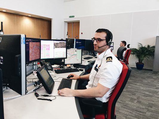A coastguard officer in a white shirt sitting at a desk