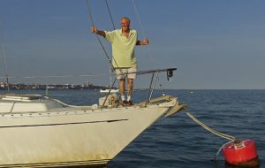 Robin Davie in a cream t-shirt on a bow of a boat
