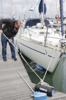 A man wearing glasses uses the Scrubbish system to clean the hull of a sadler