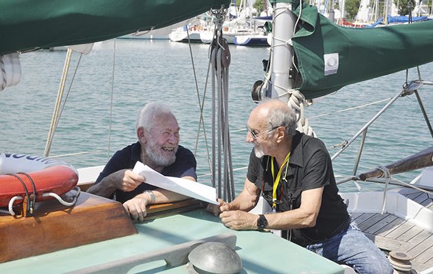 Two skippers wearing black tshirts talking on a boat