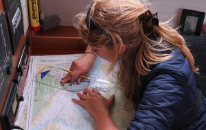 A skipper studying a paper chart below deck