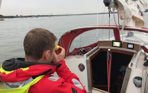 A skipper using a handbearing compass