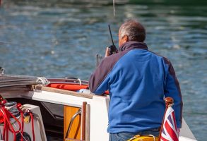 A man on a boat talks into his VHF Marine radio.