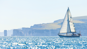 A yacht sailing off Harry's Rock, Poole. June 2022