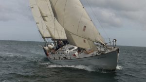 The yacht Gipsy Moth IV, with a white hull and off white sails cruising in the Solent