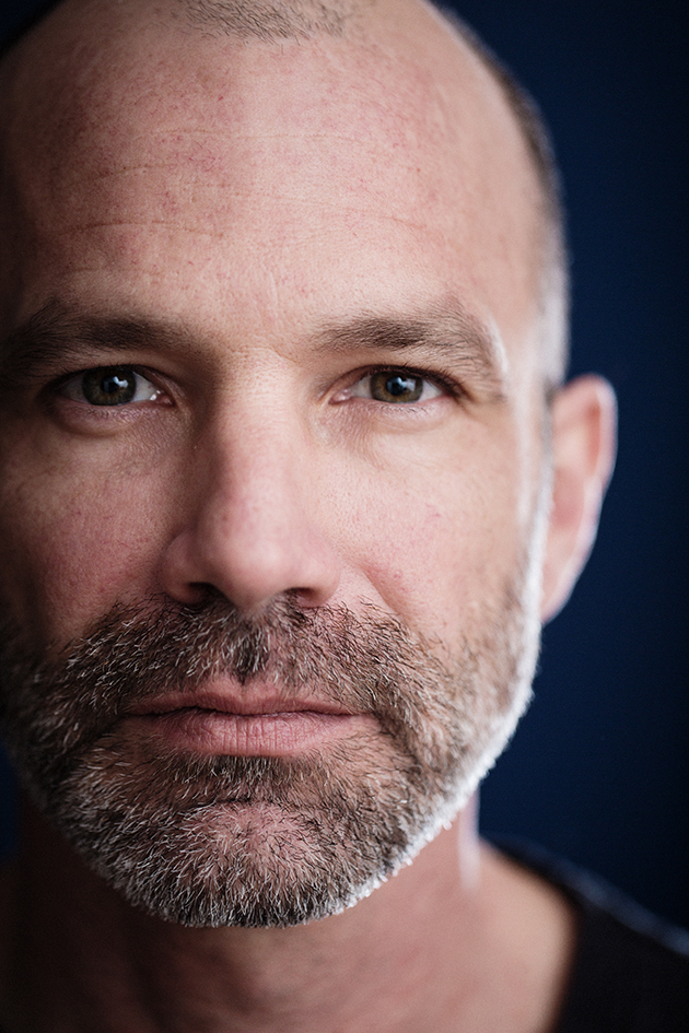A portrait of a man with a beard, half lit
