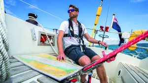 Boat navigation - a man in a black lifejacket sailing a boat with a chart in front of him