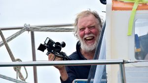 A man holding a sextant on a boat