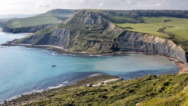 A yacht anchored in a bay by a headland
