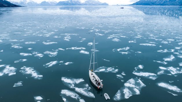 A yacht sailing through ice floes, revealing the extent of climate change in Svalbard