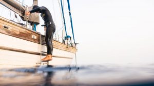 A diver in a wet suit stepping down steps on the edge of a yacht into the sea at La Gomera