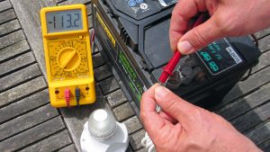 A man trying to trouble shoot marine electrics problems with a volt meter