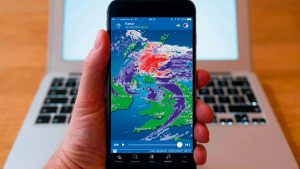 Best weather apps. A man holding a smart phone with a weather app open on it