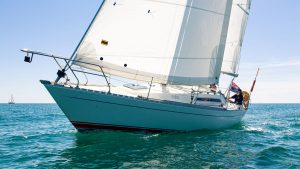 A Sigma 33 yacht sailing through the water with a man at the helm