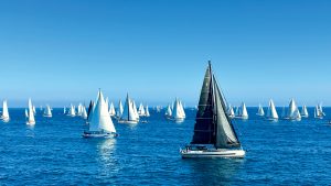 A wide shot of some yachts sailing on fairly calm seas in sunny weather.