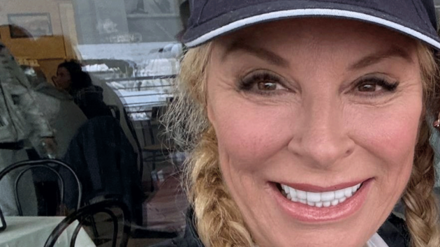 Sarah smiling at the camera, wearing smoky eye makeup and a baseball hat