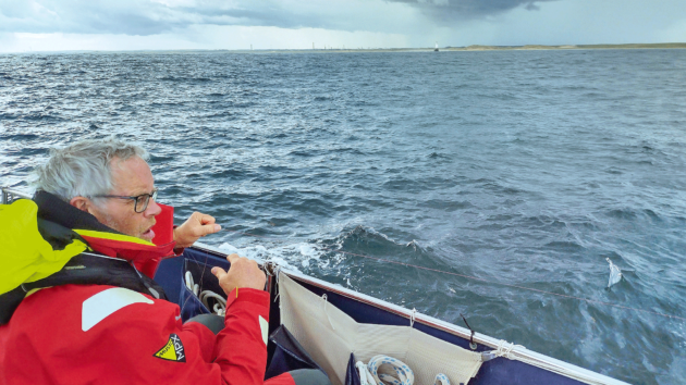 Thunder clouds loom as David checks the fishing line as they pass the snoozing dragon of Rattray Head