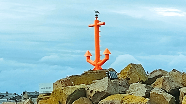 A fluorescent orange anchor marks the port hand breakwater at the entrance into Peterhead Marina