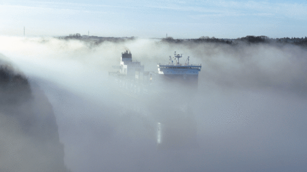 A vast container ship navigates down a misty Kiel Canal