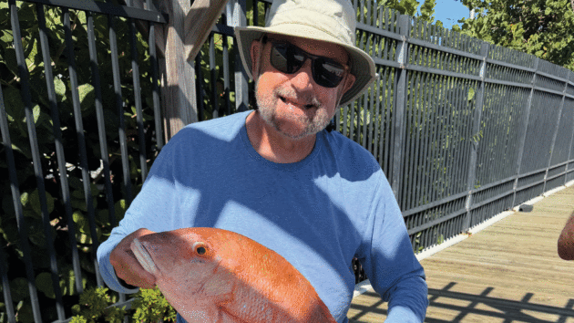 Man holding up a fish and smiling