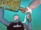 Someone in diving gear underwater next to a propeller