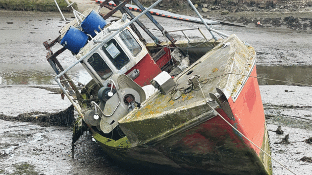 An unloved fishing boat abandoned in a mud berth in the upper reaches of the Truro River, Cornwall
