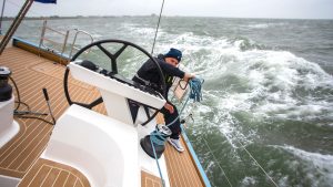 A yacht at an angle with choppy waves nehind