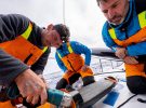 Jack Bouttell grinding away at a crack at the root of the starboard rudder of 11th Hour Racing Team during the 2022/23 The Ocean Race with crewmates Simon Fisher and Justine Mettraux.