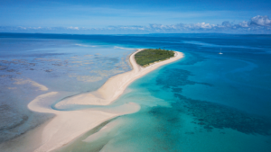 Wide birds-eye-voew pf a sand bank and turqoise sea.